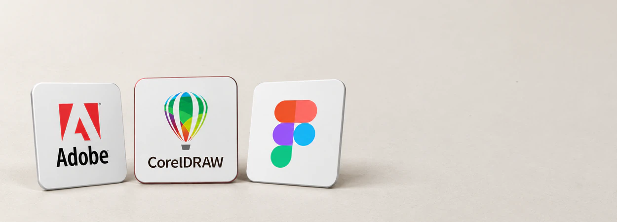 Adobe, CorelDRAW and Figma design cards standing on a desk